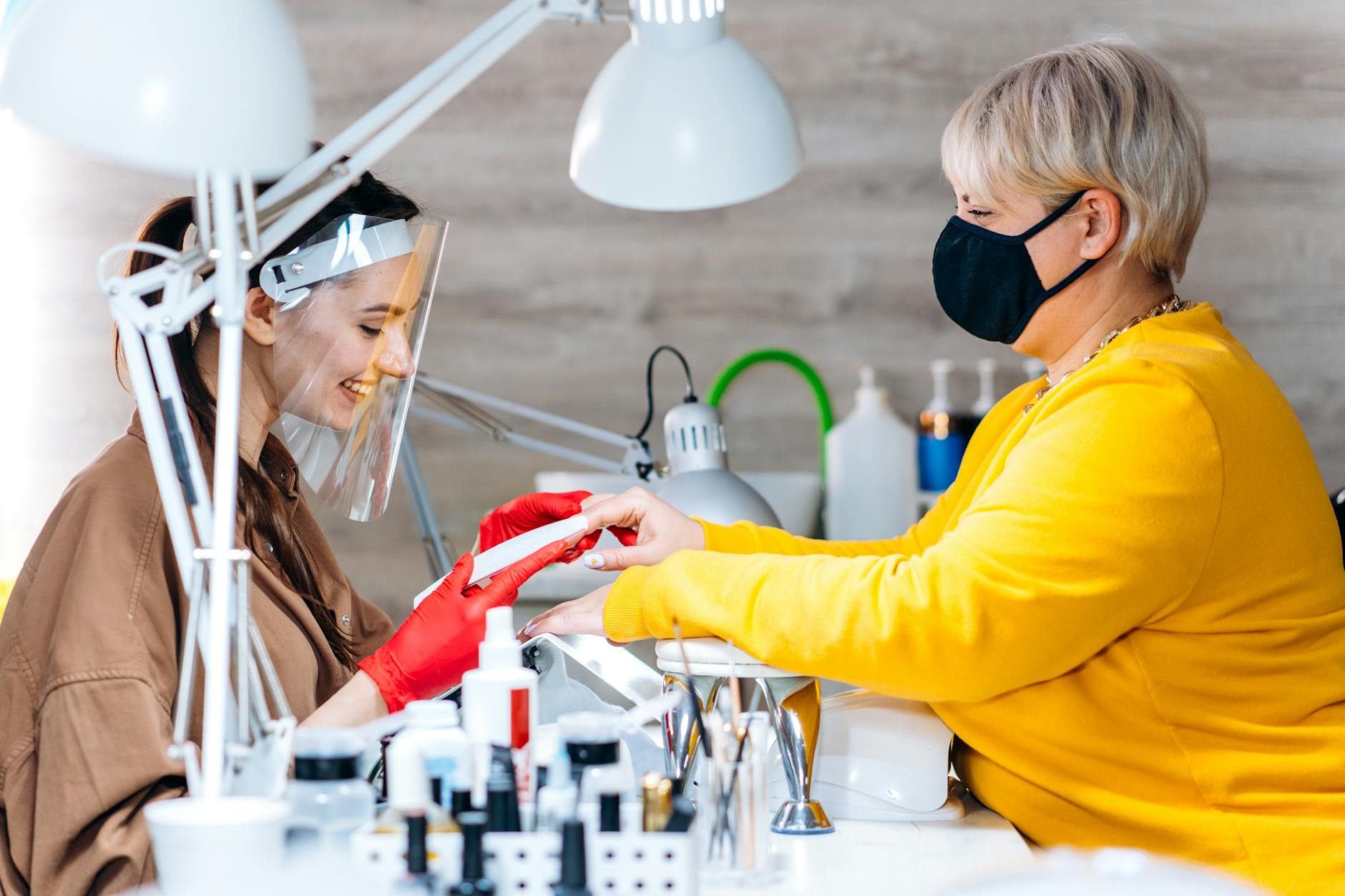 Klientki w nowoczesnym salonie podczas manicure w reżimie sanitarnym