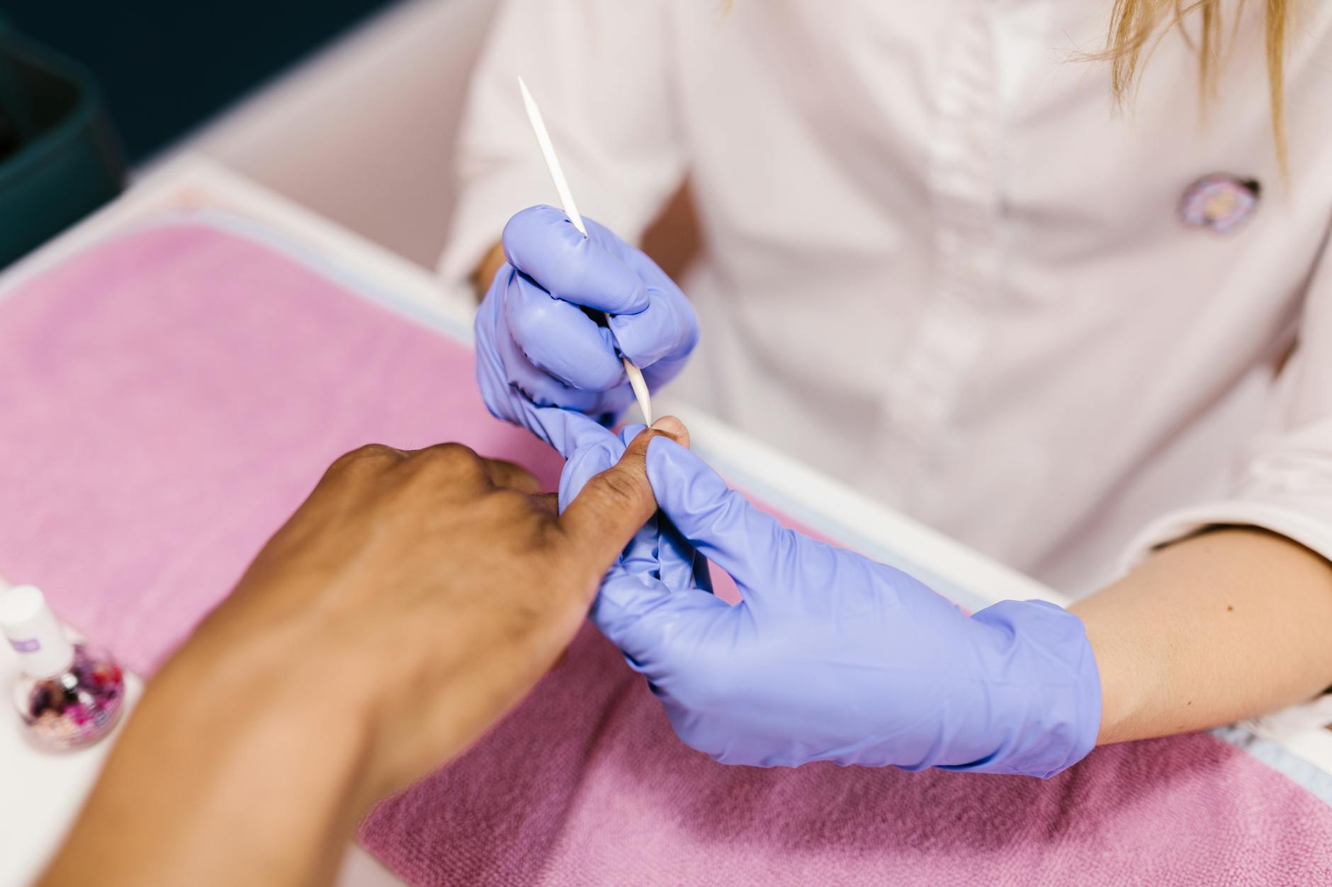 Stylistka opracowuje skórki frezem podczas manicure w salonie