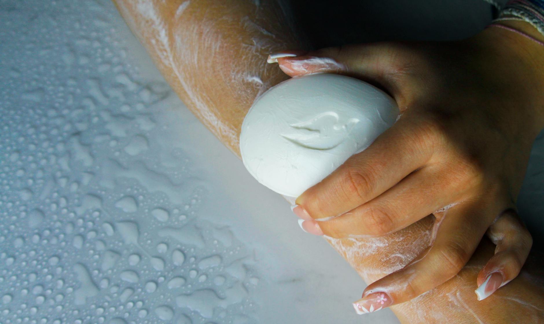 Dłonie myjące przedramię mydłem w pianie jako element higieny manicure