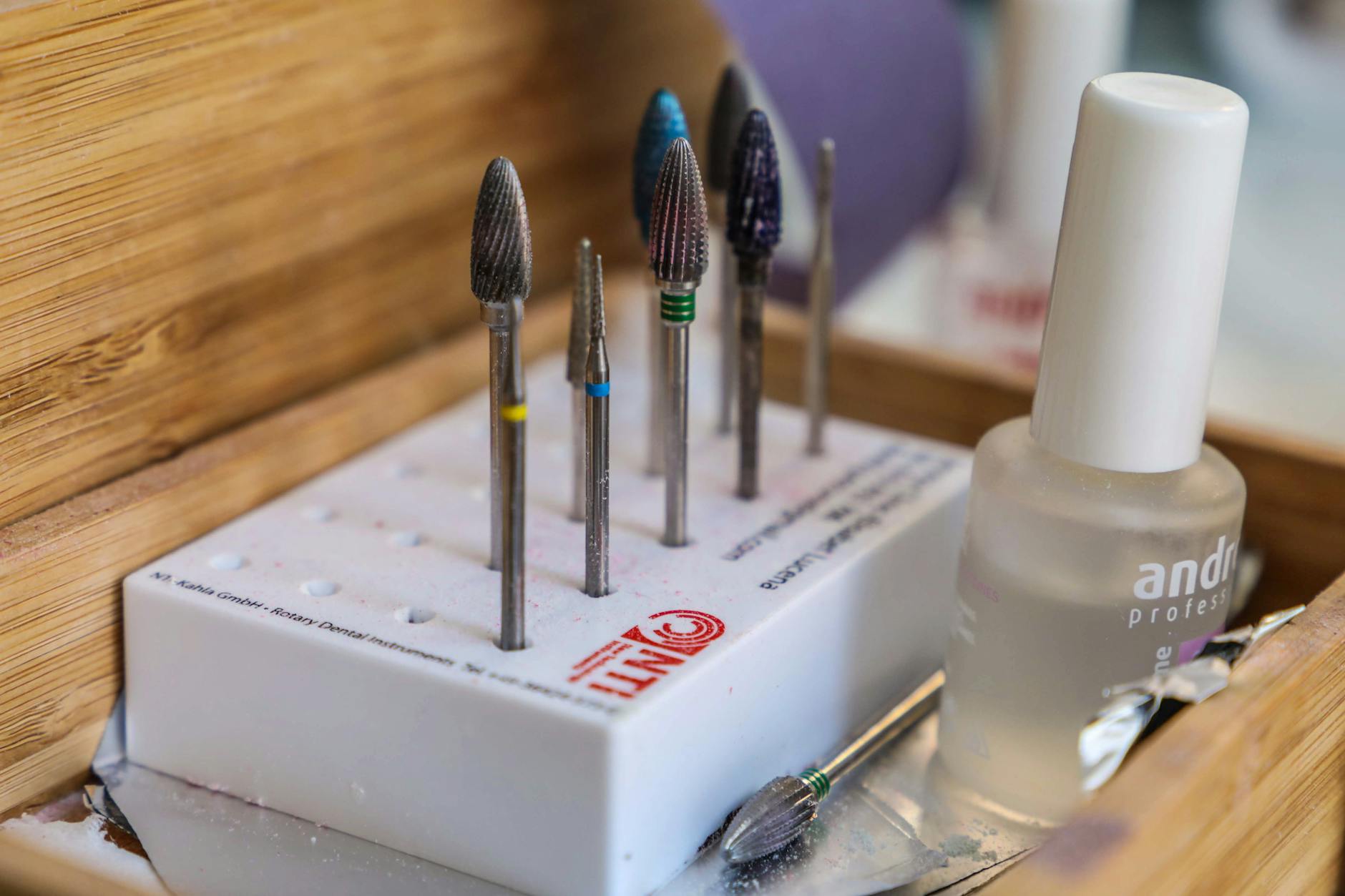 Frez ceramiczny i karbidowy obok lakieru do paznokci na stole