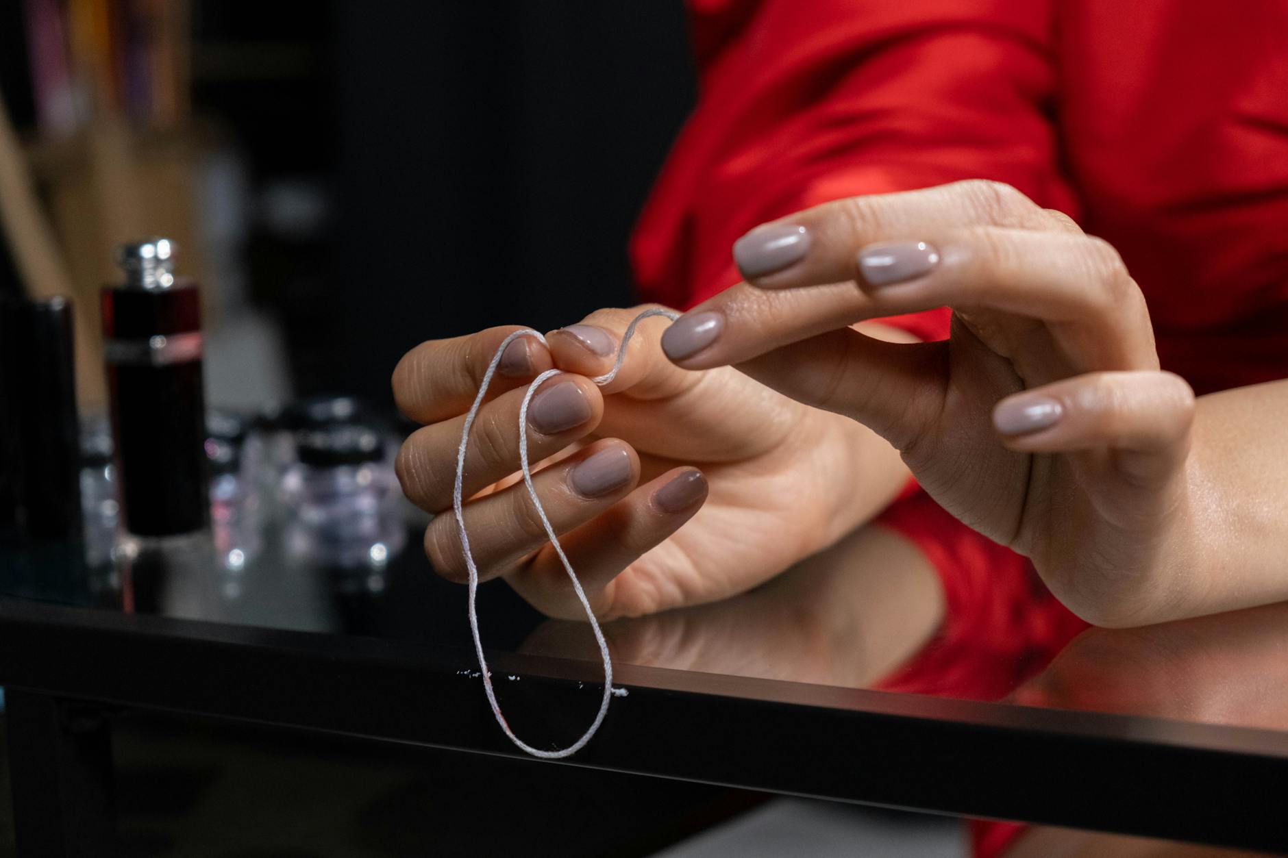 Zbliżenie dłoni z manicure hybrydowym oplatających nić