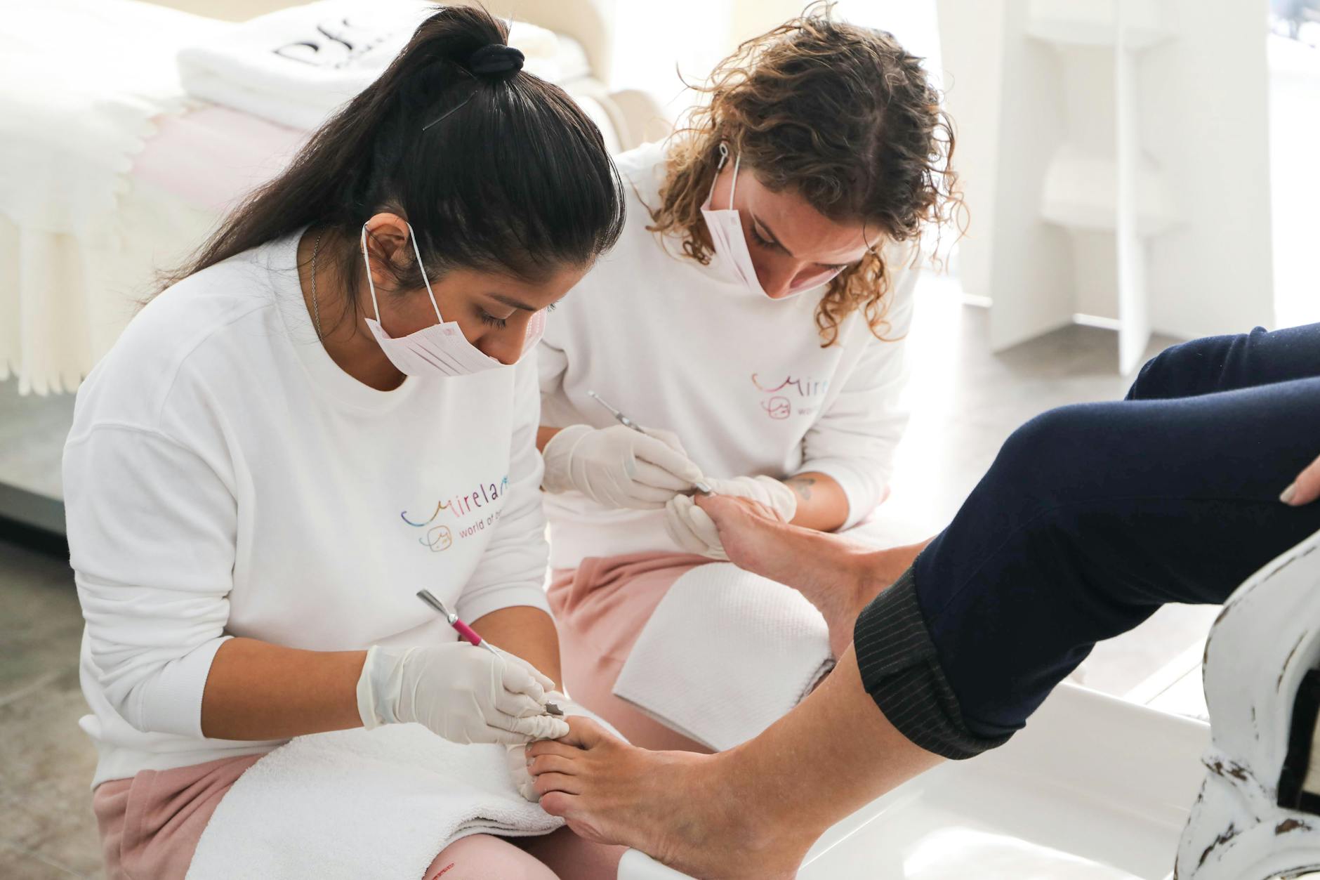 Pedicure wykonywany przez dwie stylistki w nowoczesnym salonie