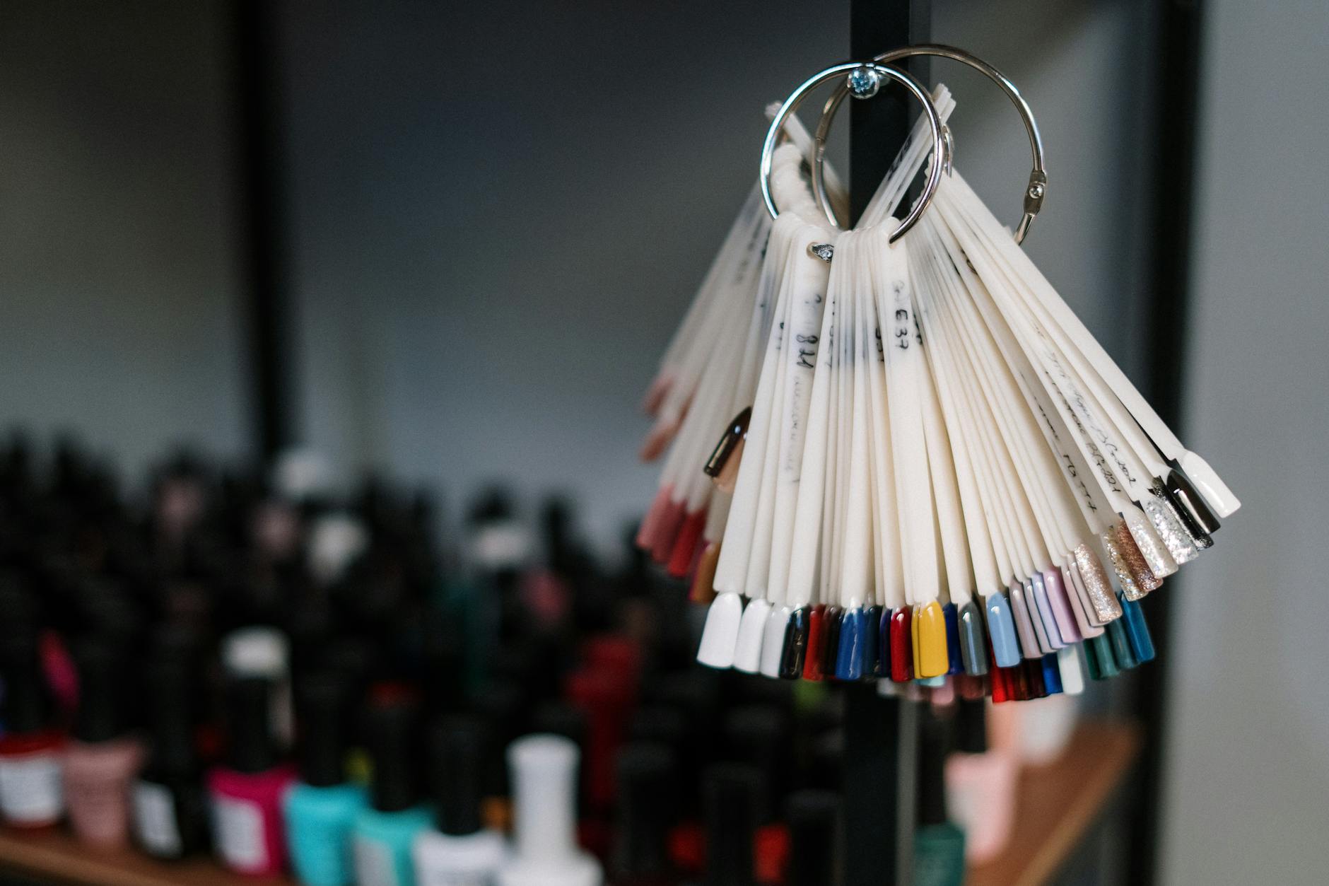 Wzorniki, próbki, ekspozytory: jak prezentować kolory, żeby klientka wybierała szybciej Kolorowe wzorniki lakierów hybrydowych na ekspozytorze w salonie manicure