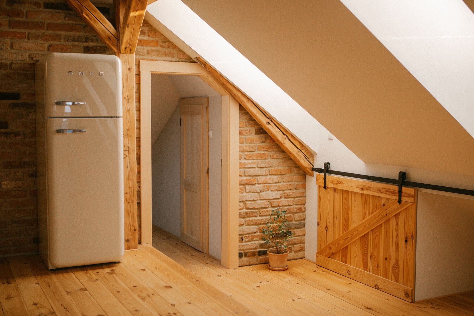 Przytulny loft na poddaszu z drewnianymi belkami i retro lodówką