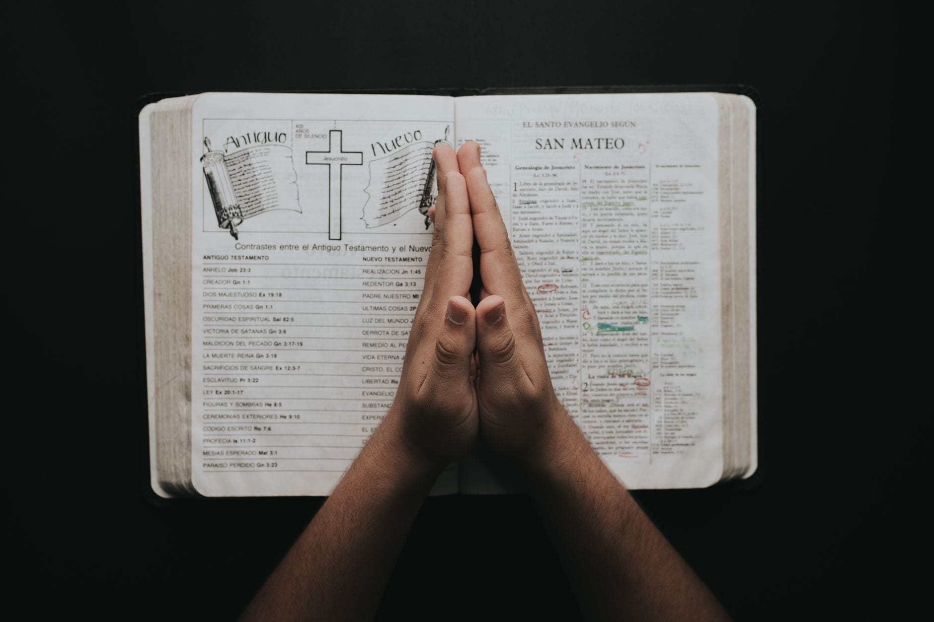 Złożone dłonie na otwartej Biblii z Ewangelią Mateusza
