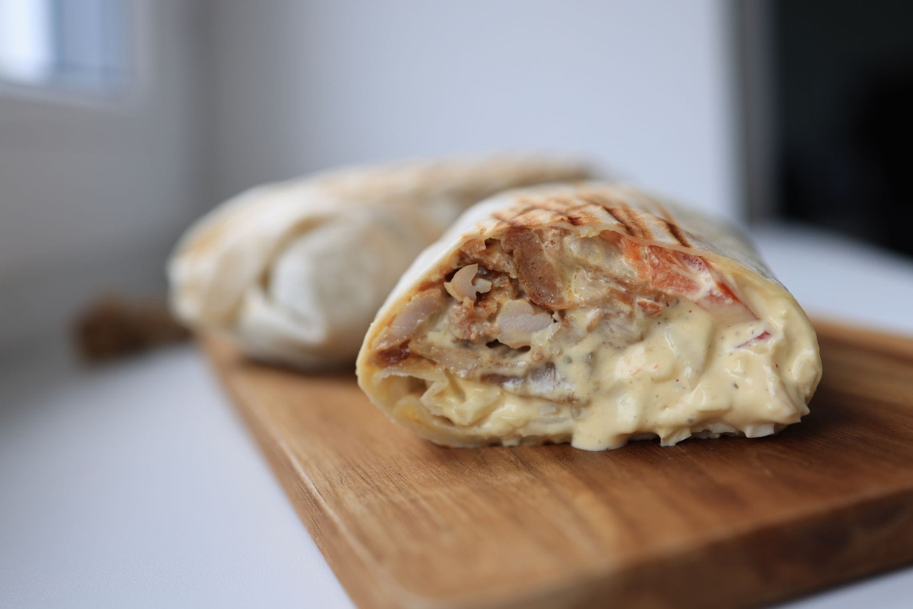 Kebab z kurczakiem i sosem na drewnianej desce do krojenia