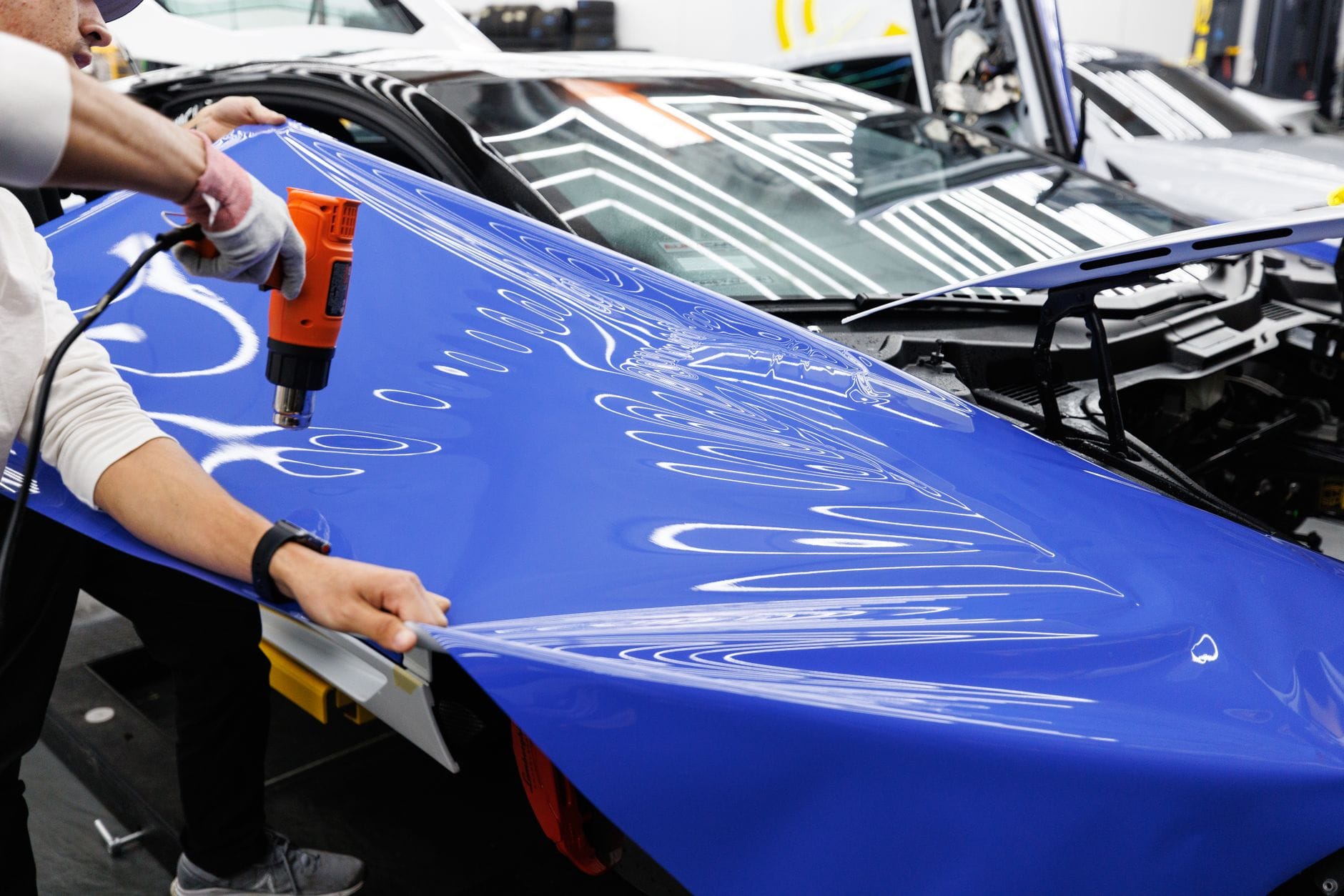 Technik w warsztacie nakłada niebieską folię winylową na auto