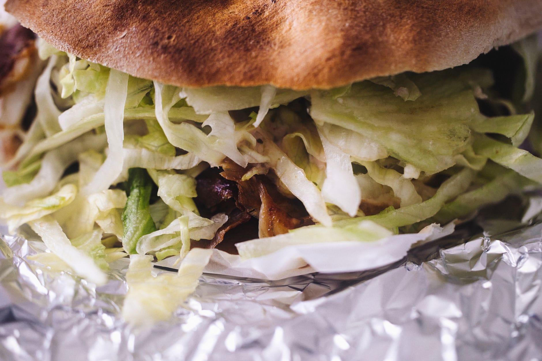 Zbliżenie na apetyczny kebab w folii z chrupiącą sałatą Zbliżenie na apetyczny kebab w folii z chrupiącą sałatą