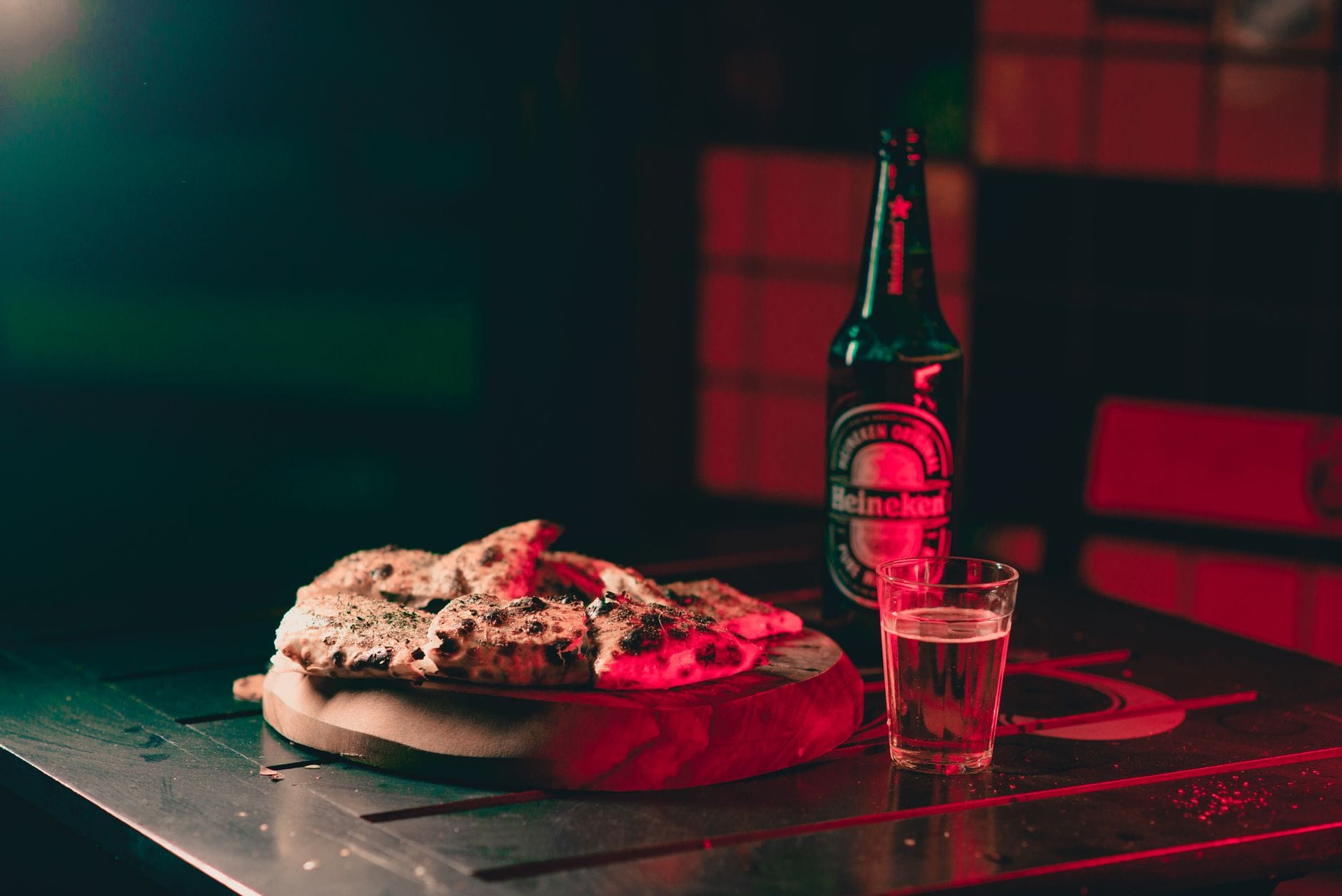 Pizza i butelka piwa Heineken na drewnianej desce w przytulnym wnętrzu Pizza i butelka piwa Heineken na drewnianej desce w przytulnym wnętrzu