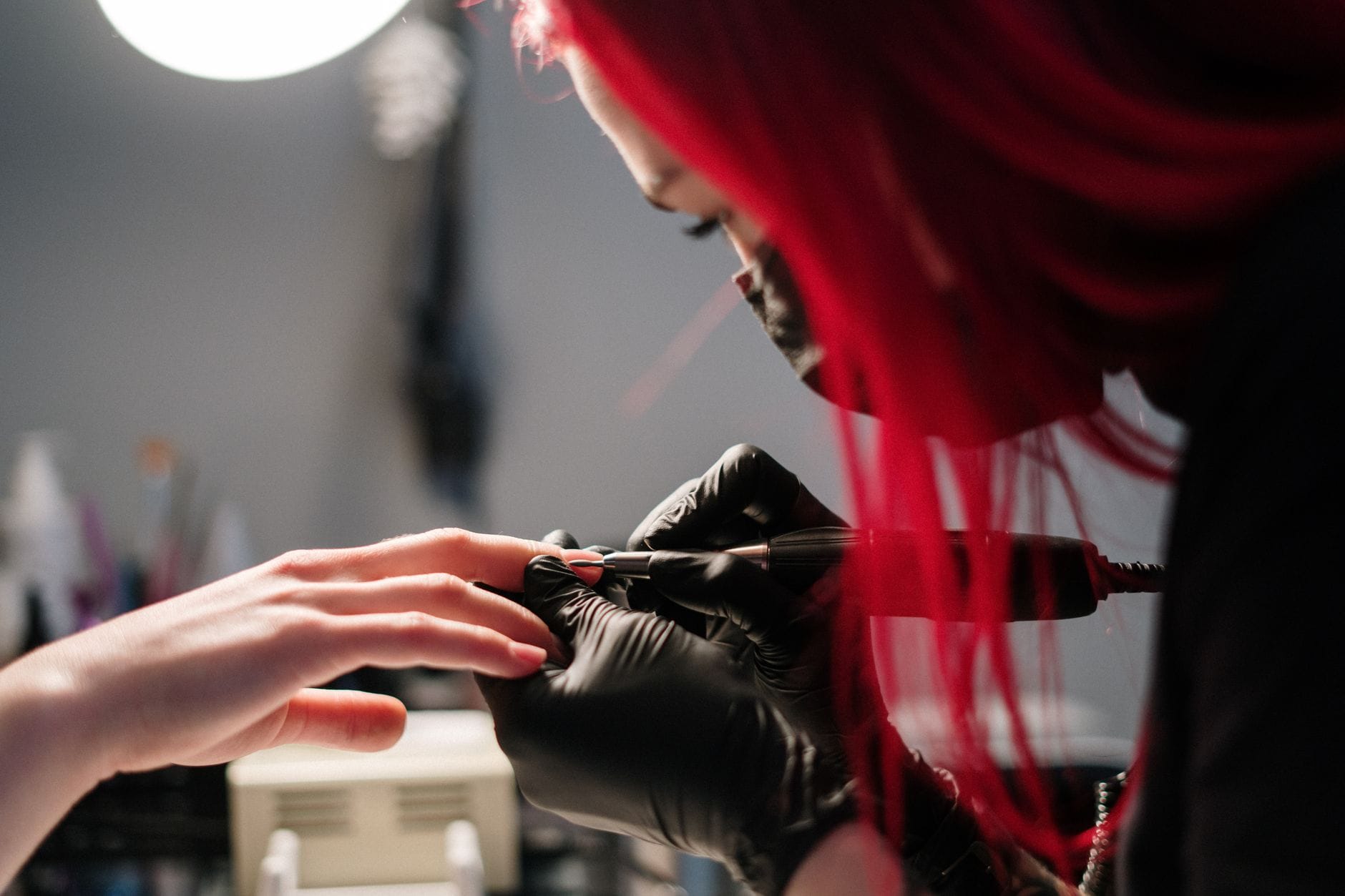 Co zrobić, gdy klientka ma brodawkę lub zmianę na palcu Stylistka paznokci w rękawiczkach wykonuje manicure klientce w salonie