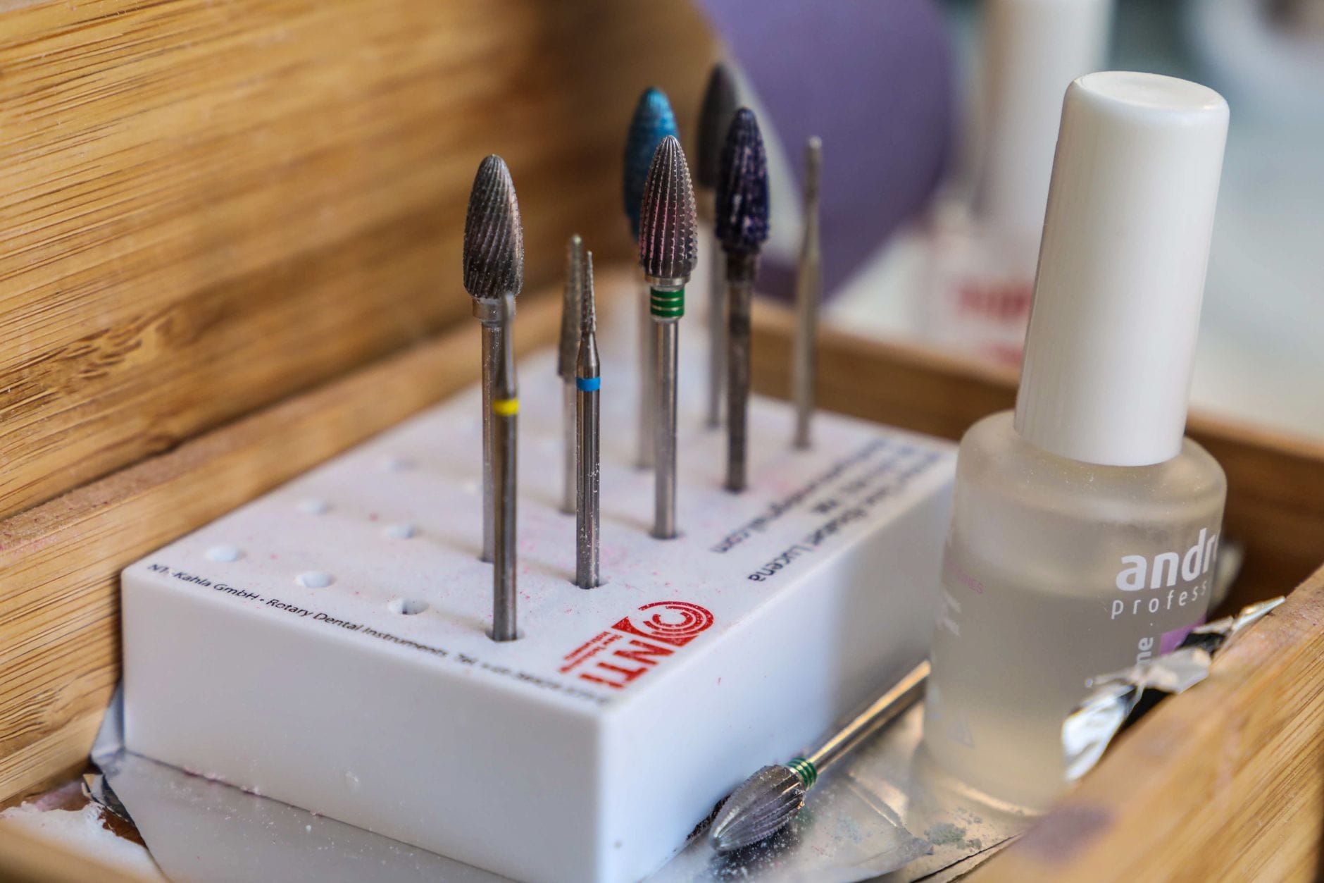 Czym różni się frez czerwony, niebieski i zielony? Kolory, gradacje i zastosowanie Zbliżenie na frezy do manicure w różnych kolorach obok lakieru
